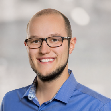 Lächelnder Mann mit Brille und blauem Hemd, der für HR Metrics als Experte für die Digitalisierung von HR-Prozessen steht.